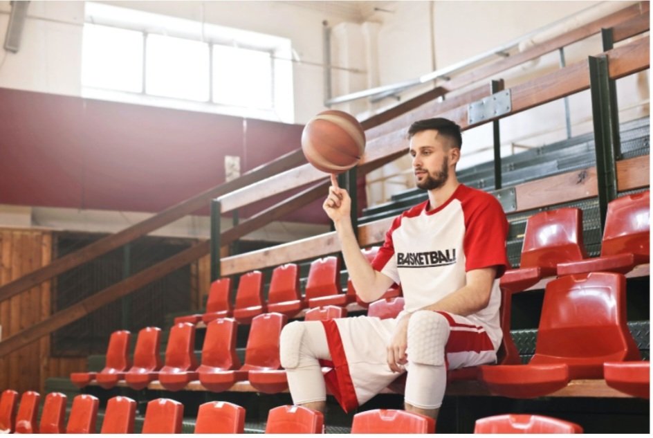 Seated basketball player spinning ball on finger
